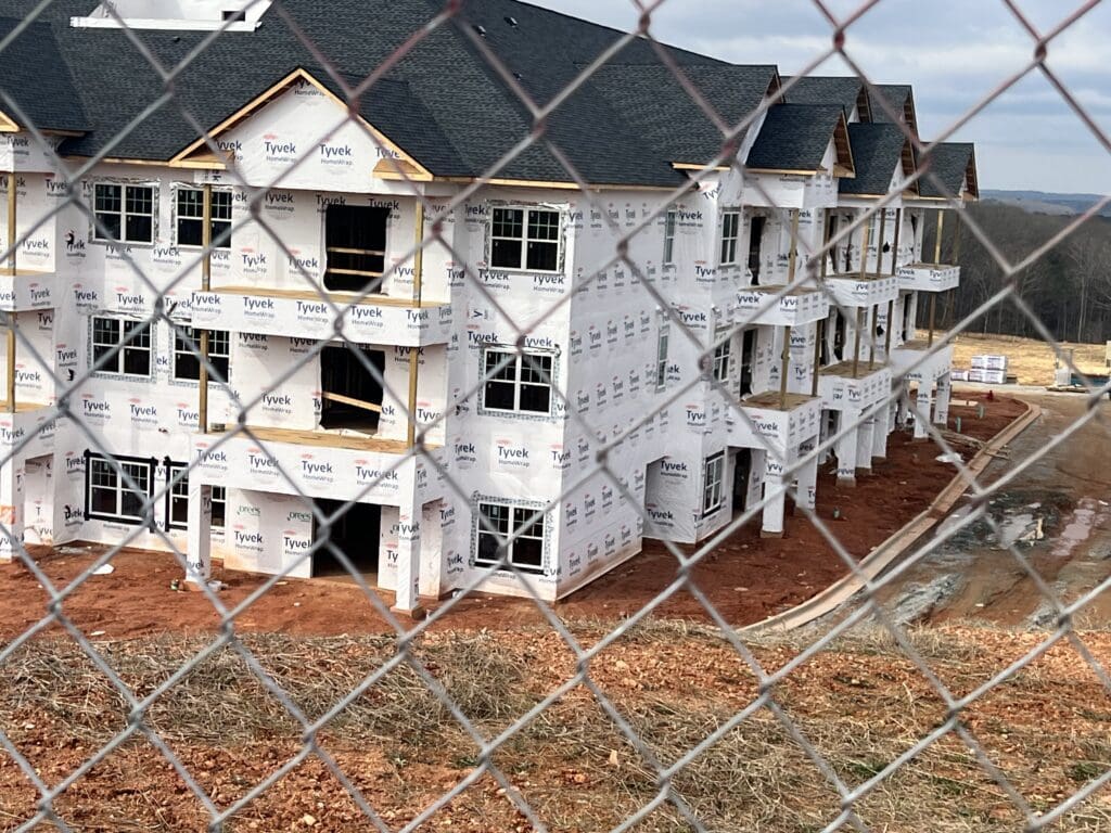 view of community building construction from behind chain link fence