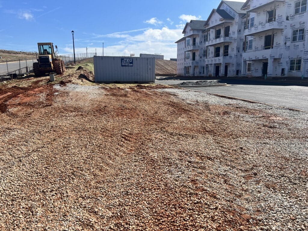 view of construction site including building, construction vehicle, and large container